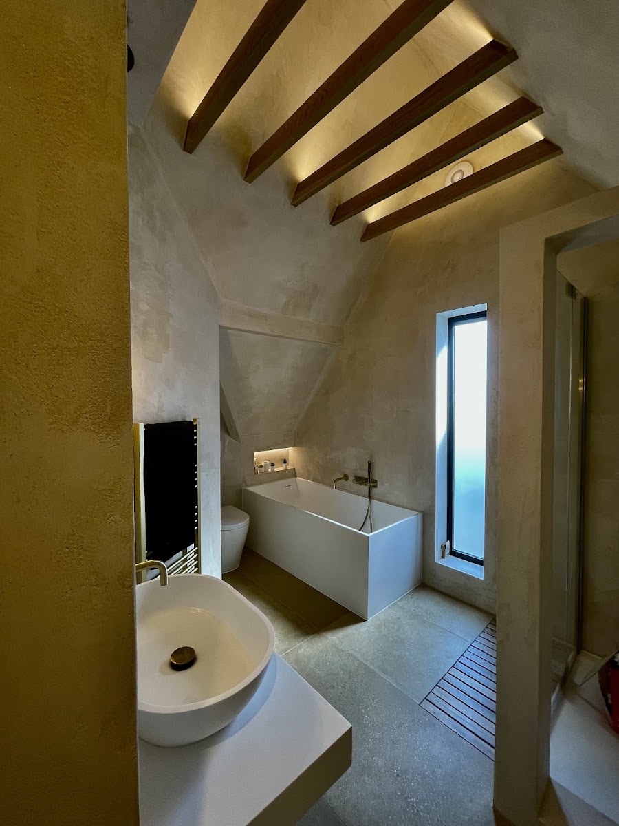 A hand-burnished plaster bathroom with an amber marmorino feature wall — work by the Venetian Plaster Service